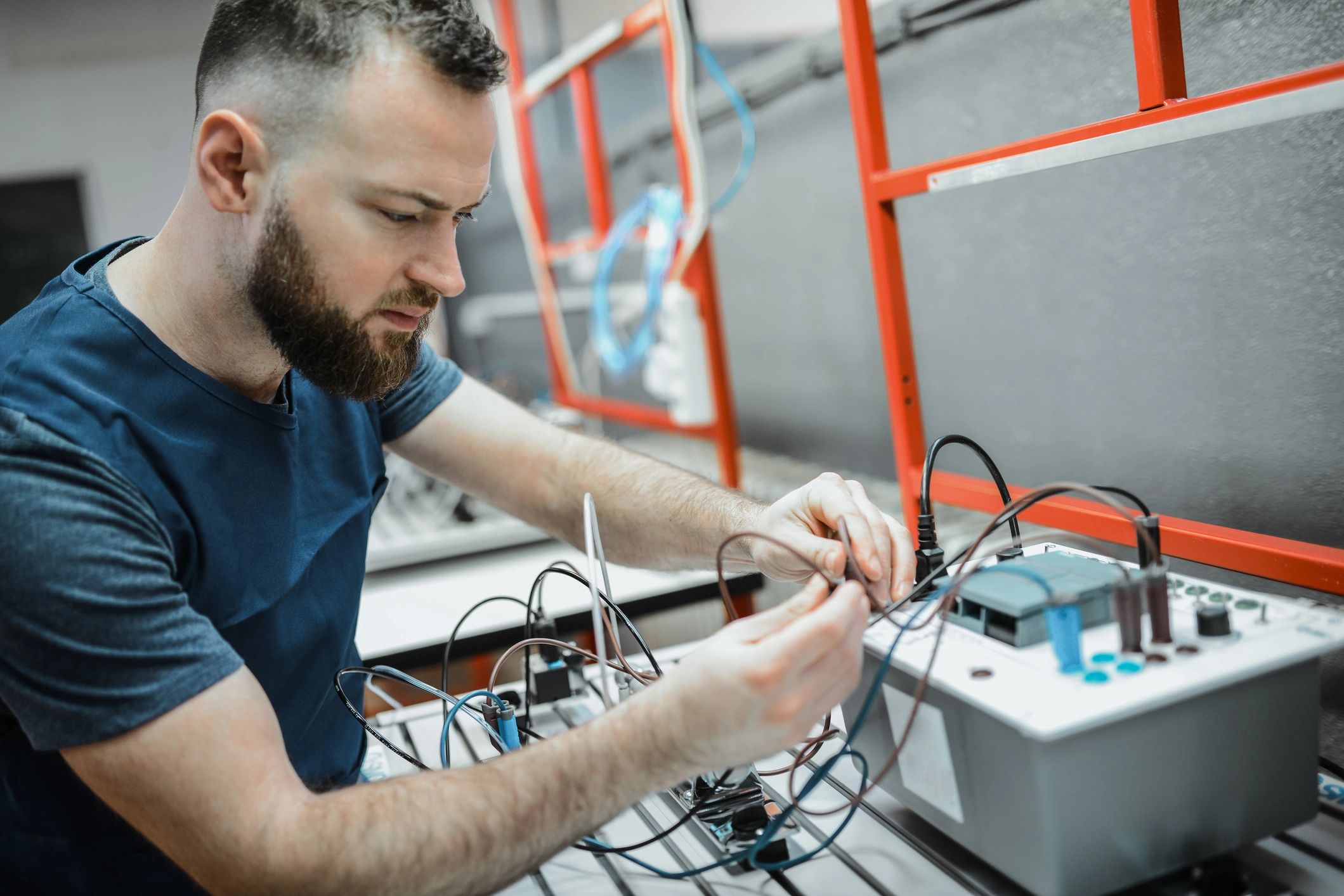 Technician wiring and testing a PLC control cabinet for industrial automation